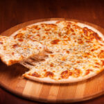 This photo shows a slice being removed from a thin-crust cheese pizza.