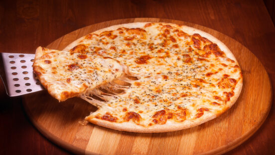 This photo shows a slice being removed from a thin-crust cheese pizza.