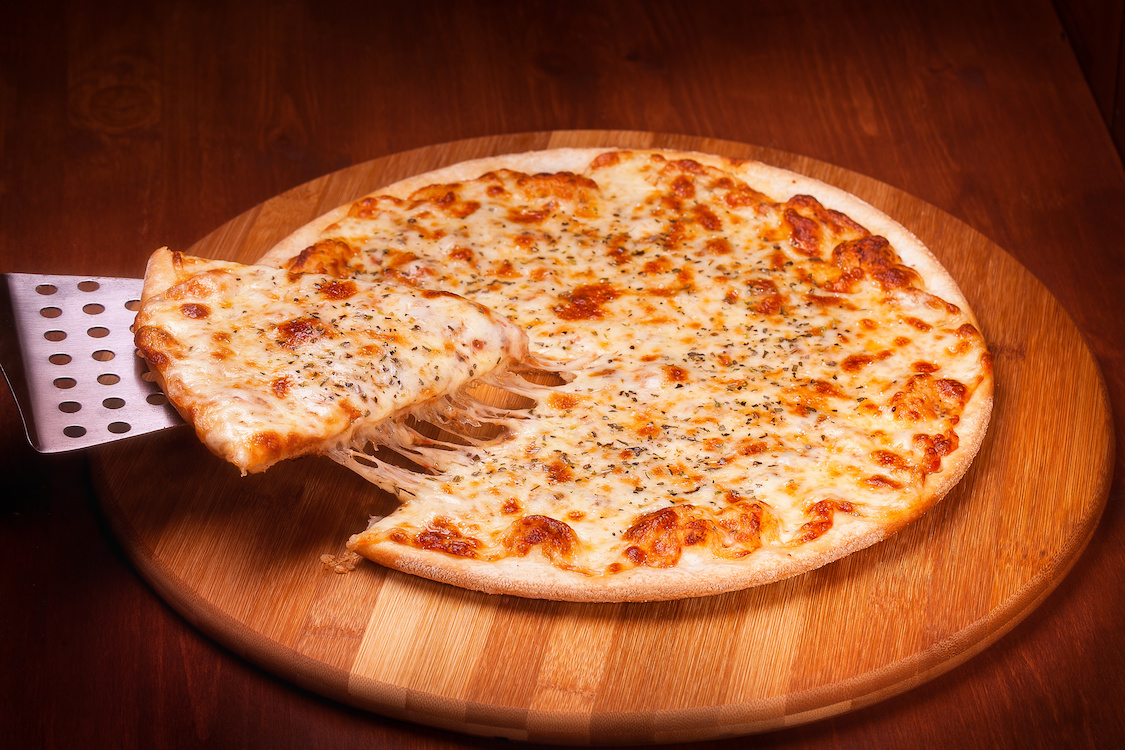 This photo shows a slice being removed from a thin-crust cheese pizza.