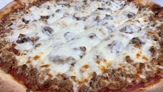 This photo shows a Quad Cities-style pizza loaded with cheese on top, plus mushrooms and sausage.