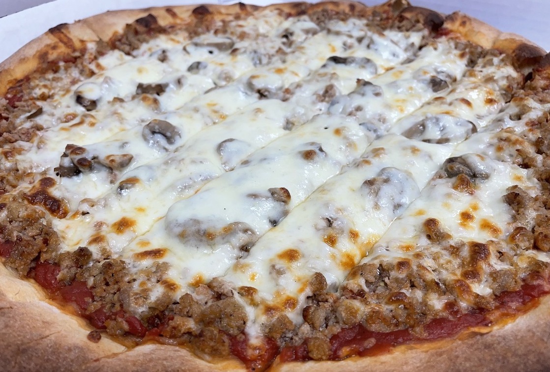 This photo shows a Quad Cities-style pizza loaded with cheese on top, plus mushrooms and sausage.