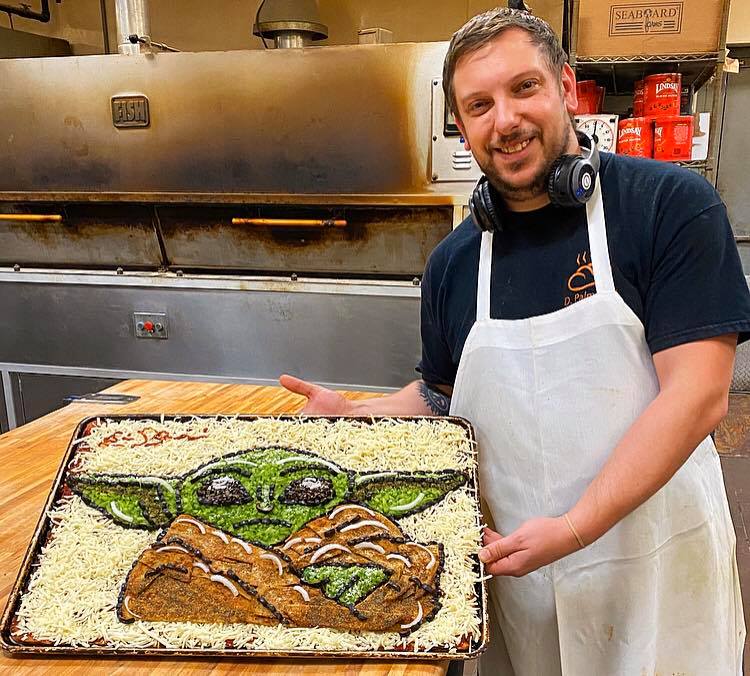 this photo shows Eric Palmieri with his pizza art, a Baby Yoda pizza