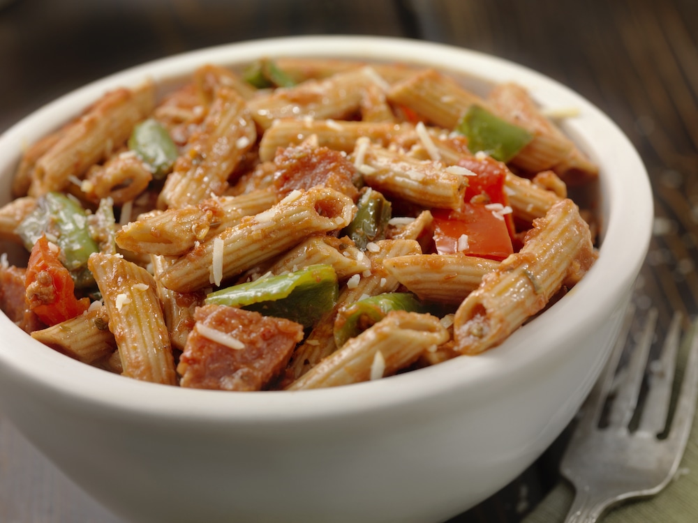 this photo shows a tasty-looking bowl of gluten-free penne pasta with sausage and peppers