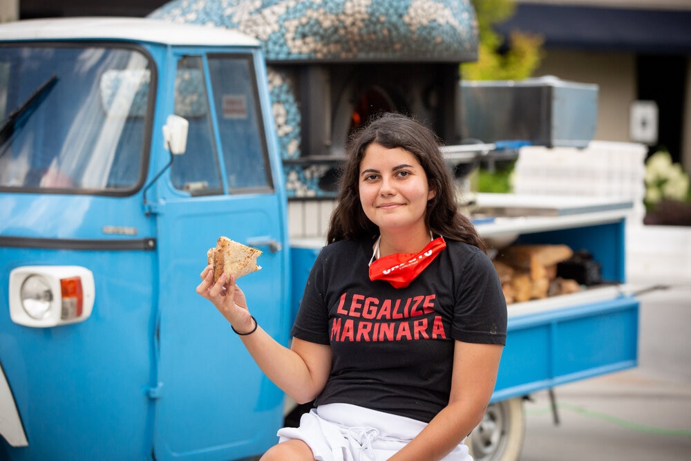 this photo shows Sofia Arango eating a slice in front of Atlanta Pizza Truck