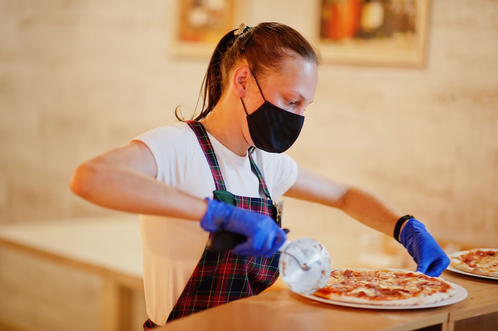 this photo of a woman slicing a pizza shows a restaurant worker who would be affected by an increase of the minimum wage