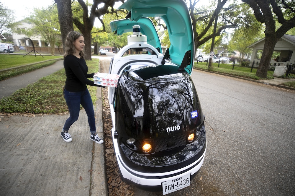 this photo shows a Domino's customer retrieving a pizza from R2, the robotic pizza car from Nuro