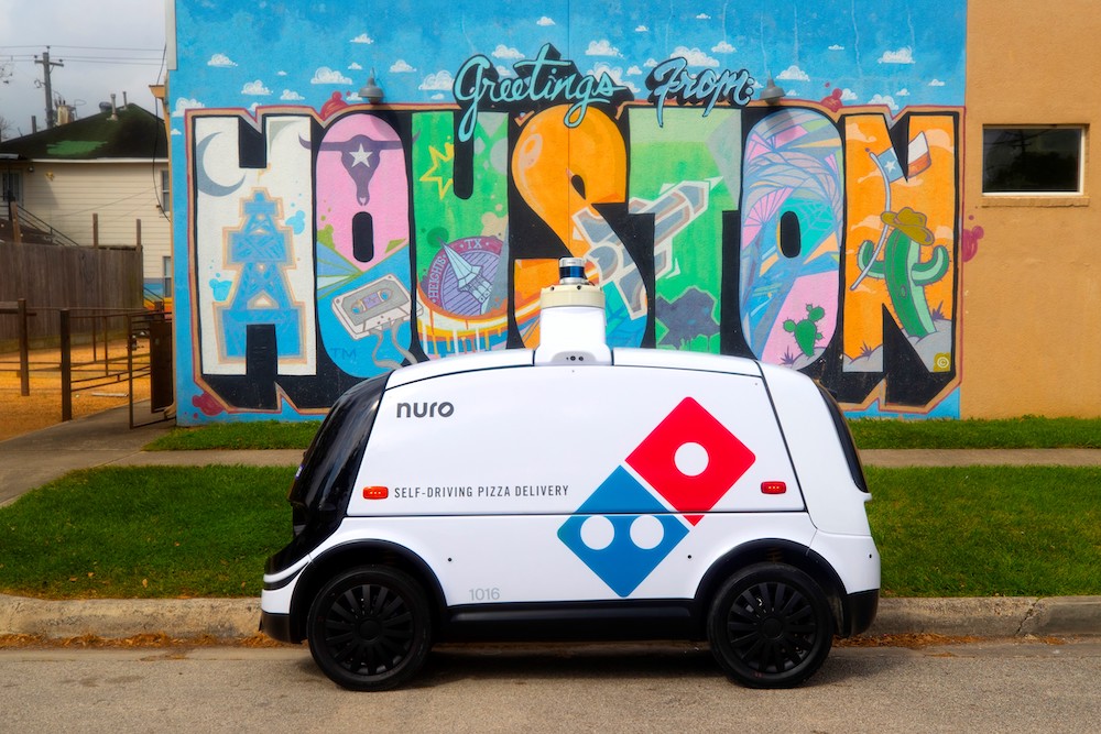 this photo shows Domino's self-driving pizza delivery car in front of a bright Houston, Texas mural