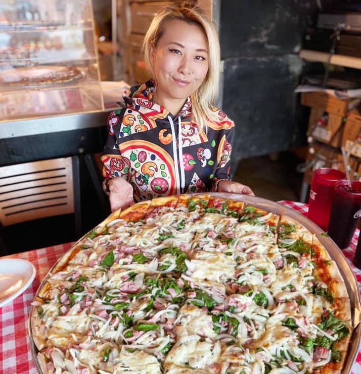 this photo shows competitive eater Raina Huang trying a pizza at Firehouse Pizzeria