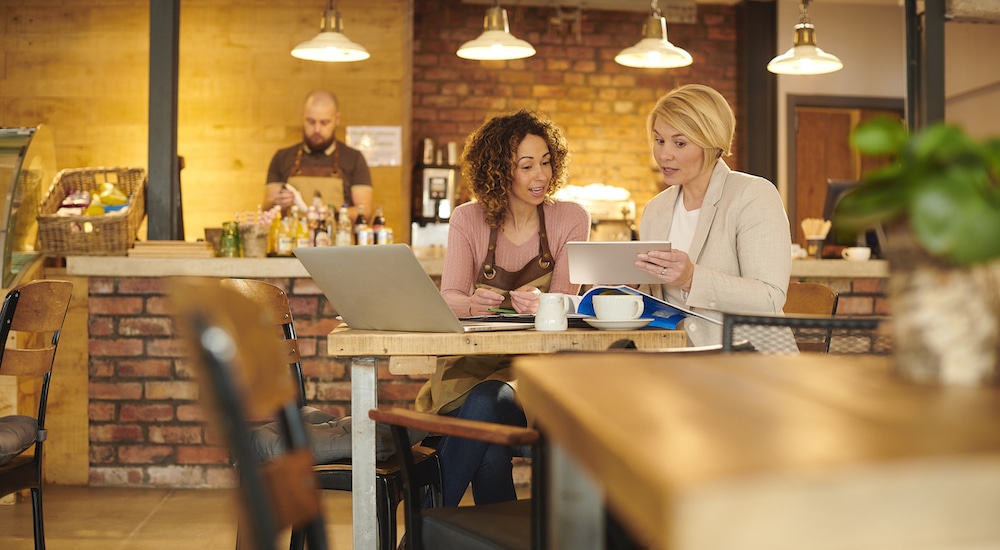 this photo shows a female restaurant owner discussing a loan with a bank representative