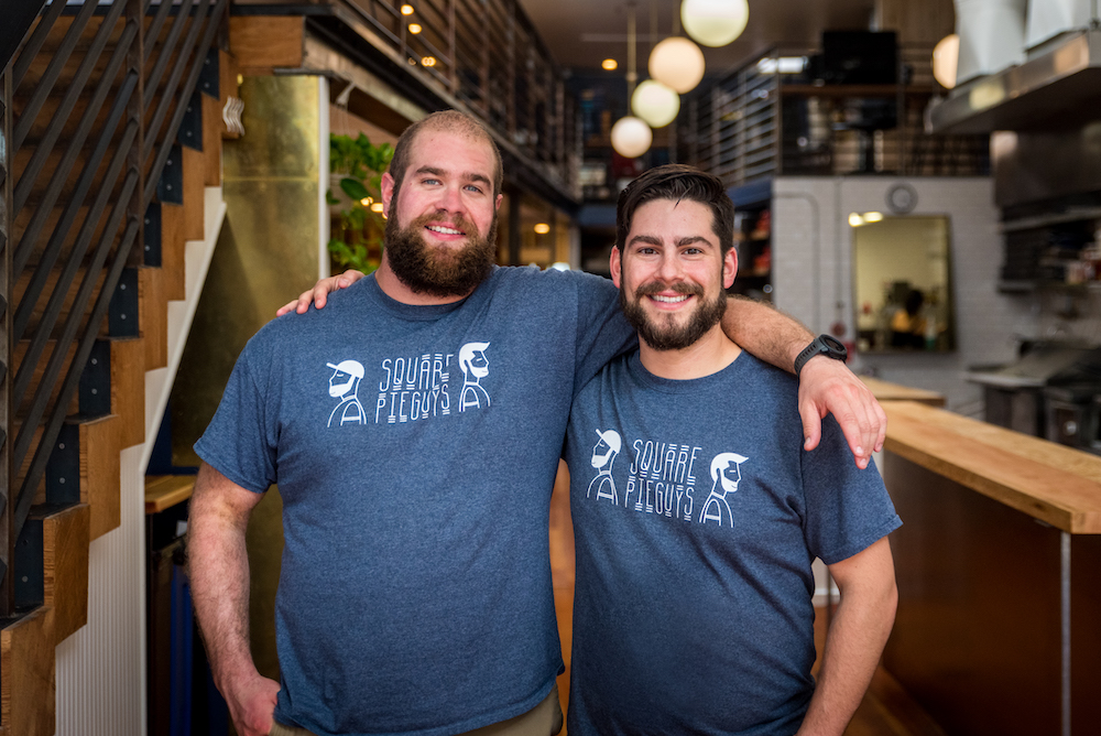 this photo shows Danny Stoller and Marc Schechter, co-owners of Square Pie Guys, with their arms around each other and smiling