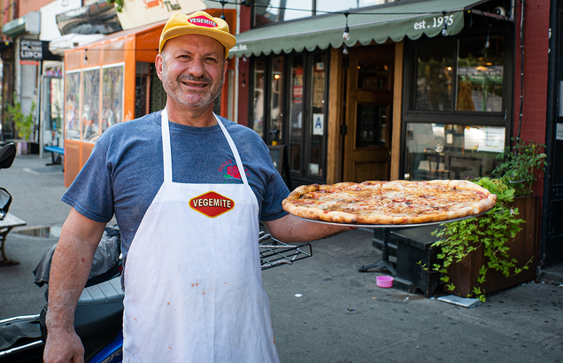 this photo shows Giovanni Fabiano displaying his Vegemite pizza at Rosa's Pizza