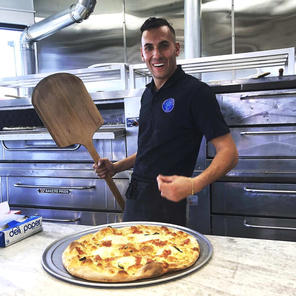 this photo shows Peter Izzo with a pizza he made at Peter's Pizzeria