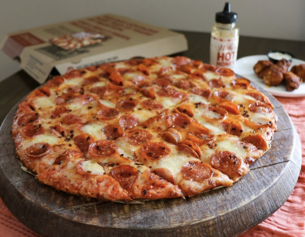 this photo shows a Donatos pepperoni pizza next to an order of chicken wings