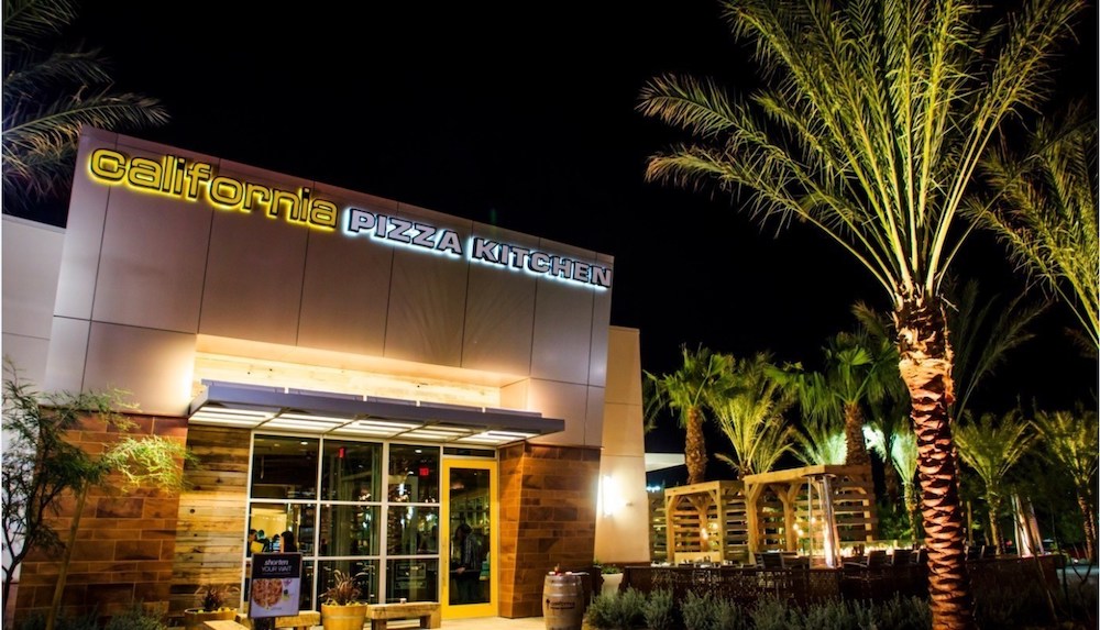 this photo shows the beautifully lit exterior of a California Pizza Kitchen restaurant at night