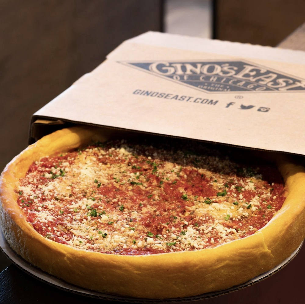 a Chicago-style deep-dish pizza peeks out of a Gino's East-Los Angeles carryout box