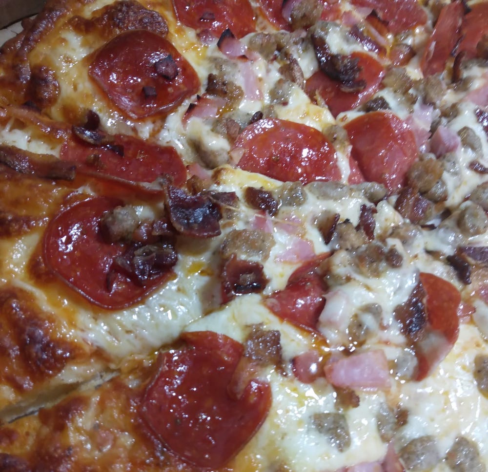 this photo is a close-up of a pizza topped with pepperoni, sausage and other pork meats as well as mozzarella cheese