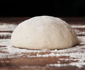 Homemade yeast dough ball for pizza on floured wooden table