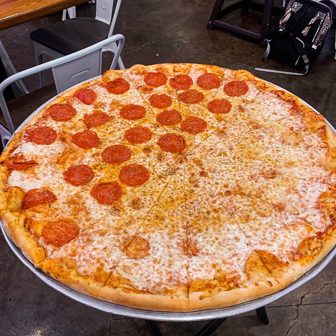 a really big pizza topped with cheese on one side and pepperoni and cheese on the other side.