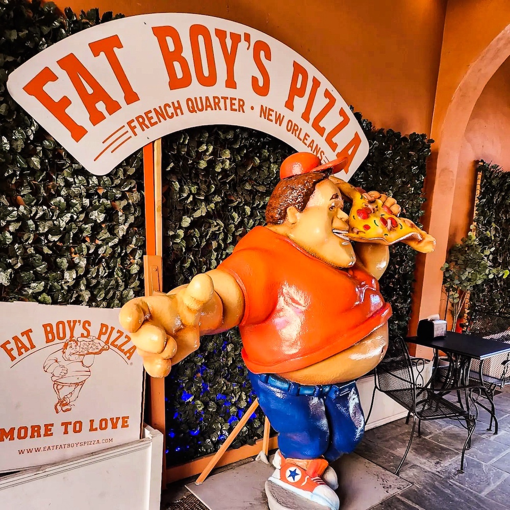 a large statue of the Fat Boy's Pizza character in a t-shirt standing in front of the pizza chain's sign