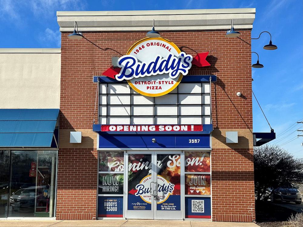 this shows the exterior of a new Buddy's location, with a brick facade, a large Buddy's sign at the top and an "Opening Soon" banner