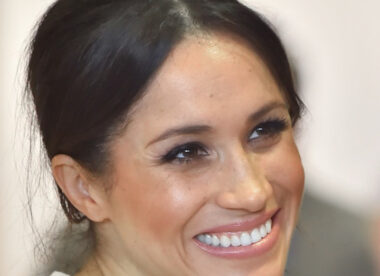 this is Meghan Markle with her hair pulled back, smiling and wearing a white blouse