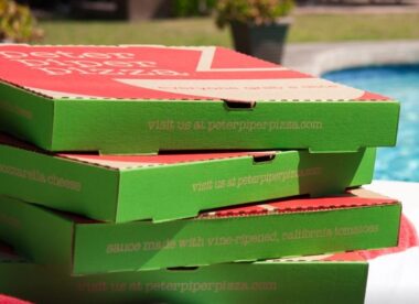 a stack of green and red Peter Piper Pizza boxes next to a swimming pool just barely visible on the right side