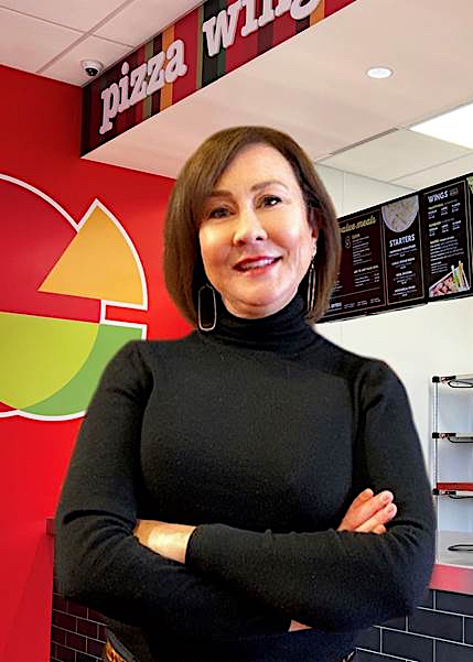 Tanya Sparkman, wearing a black sweater, stands in front of the ordering counter at a Peter Piper Pizza location