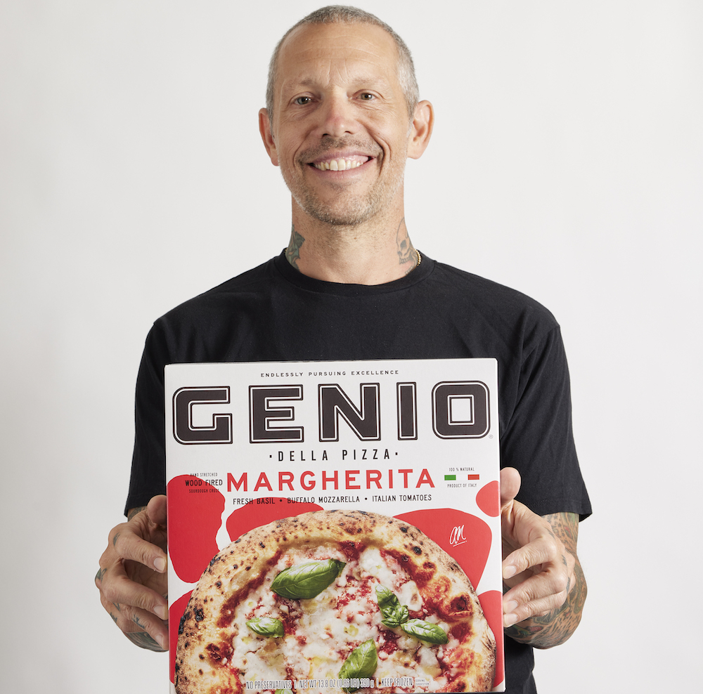 this photo shows Anthony Mangieri, wearing a black t-shirt and visible tattoos on his neck, posing with a Genio Della Pizza box and smiling
