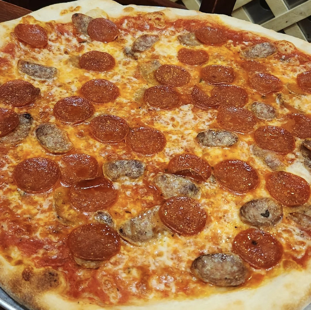 this is a close-up photo of a classic New York style pizza topped with pepperoni and Italian sausage