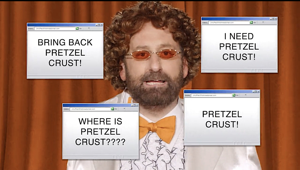 this is a screenshot from the Little Caesars video showing the spokesperson talking about the alleged corn-cob crust along with pop-up graphics that refer to a pretzel-crust pizza