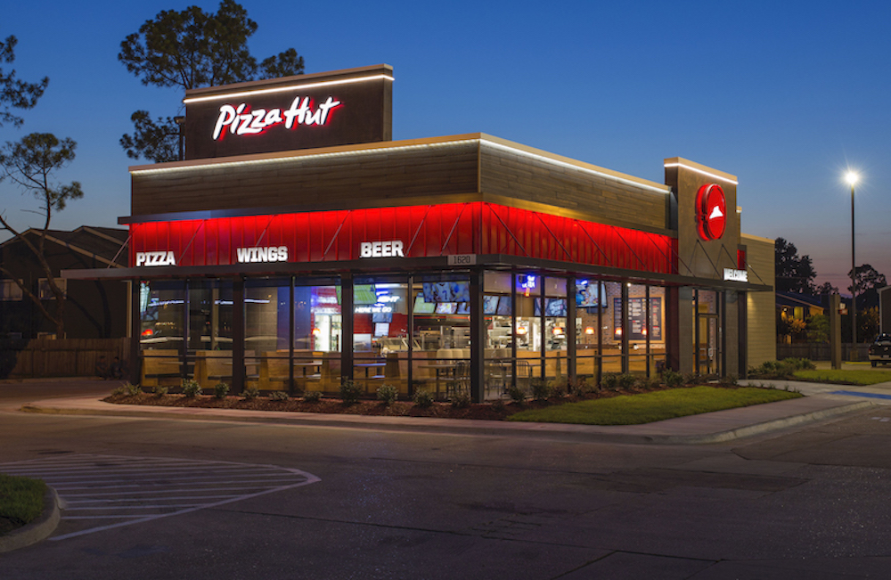 this is a nighttime scene showing the brightly lit exterior of a Pizza Hut restaurant