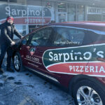 here is a driver getting into an electric delivery car with the Sarpino's logo