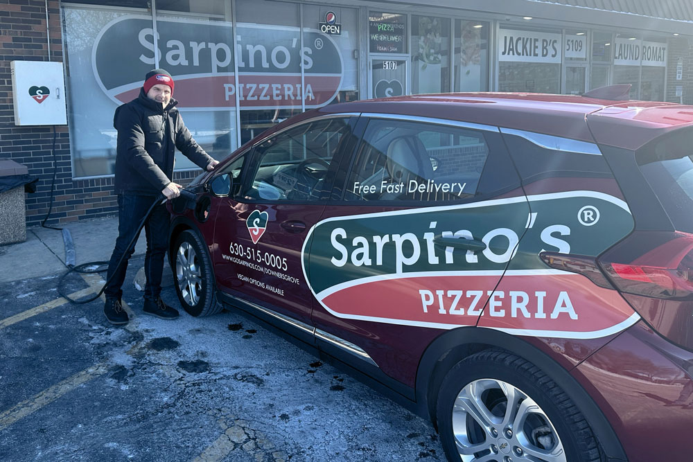 here is a driver getting into an electric delivery car with the Sarpino's logo