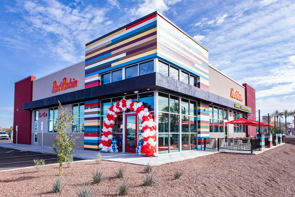 this photo shows the exterior of a Red Robin restaurant set against a beautiful blue sky with streaks of white clouds overhead