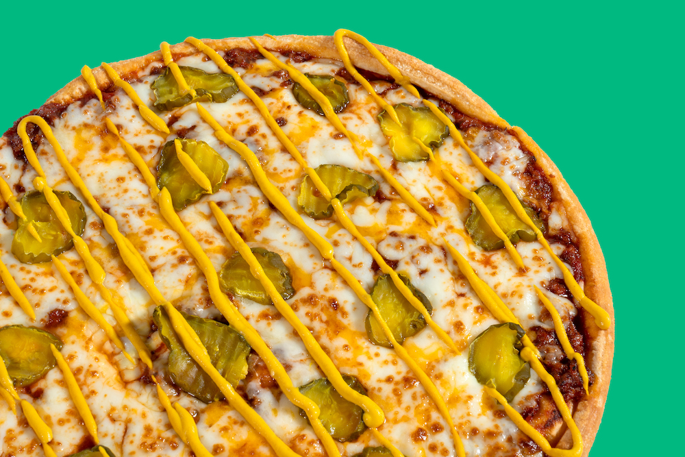 this is a close-up of a Sloppy Joe Pizza topped with ground beef, a Sloppy Joe sauce, several cheeses and pickle slices