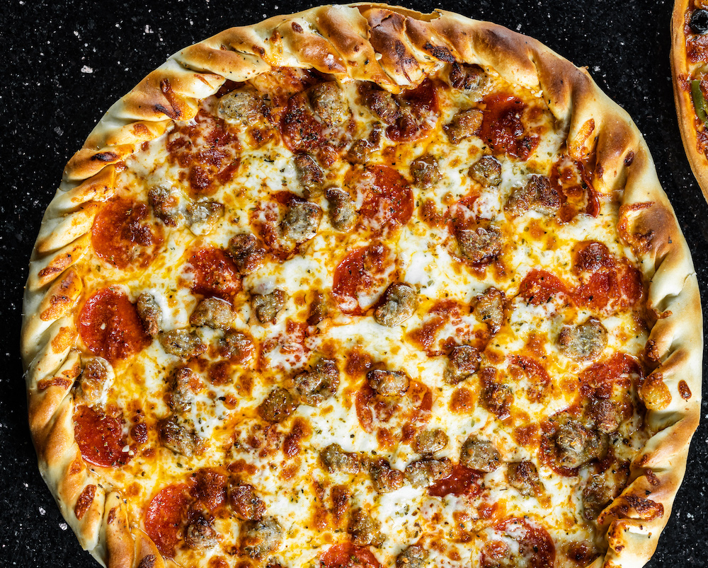 this photo shows a Dallas-style pizza with a braided crust and sausage and pepperoni toppings