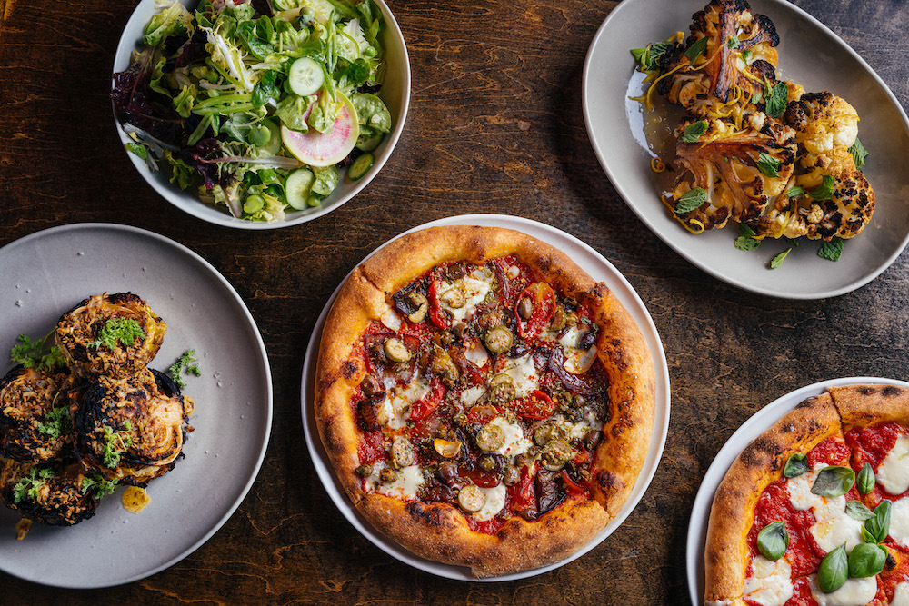 this image shows a variety of Pizzeria Mozza menu items, including two pizzas, a salad and grilled cauliflower