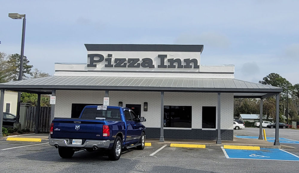 this shows the white exterior of a Pizza Inn location in Brunswick, Georgia, with a dark blue pickup truck parked out front