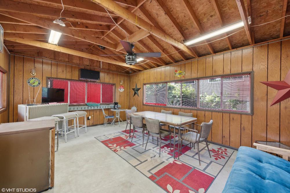 this photo shows the interior of the summer cottage with windows and blinds, a large table with chairs and a blue sofa