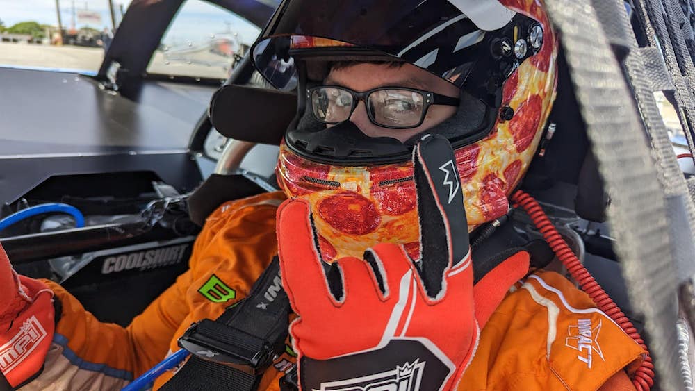 this photo shows Brayton Laster in full racing gear behind the wheel of his car