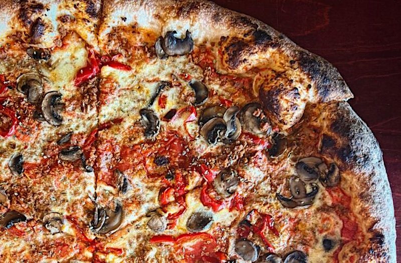 this photo shows a close-up of a pizza made with vegan sausage, mushroom and other plant-based ingredients