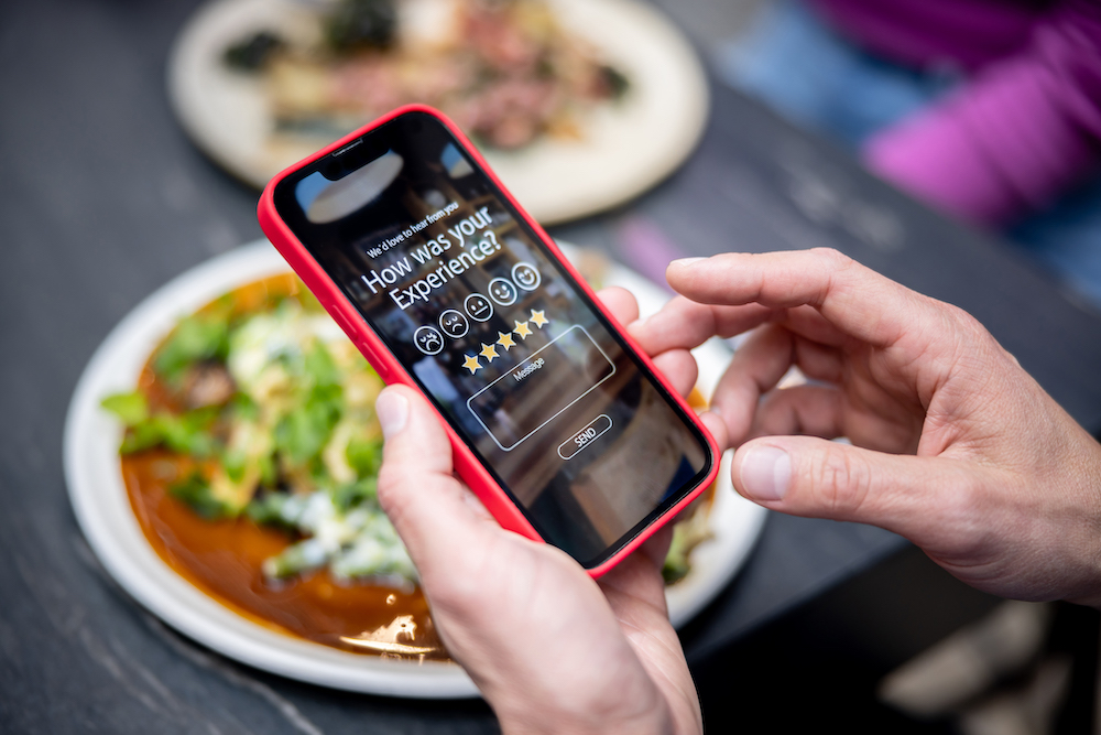 Close-up on a man rating his experience at a restaurant using an app on a cell phone