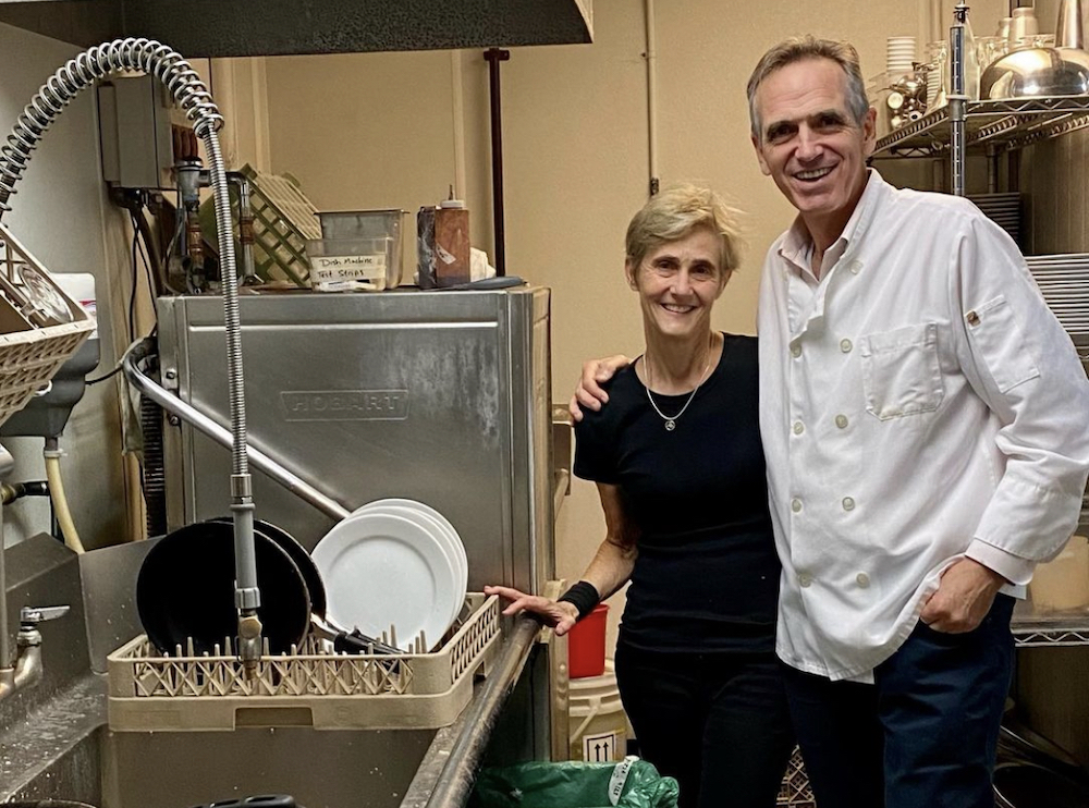 this photo shows Laurie and Peter Danis standing together at the dishwashing station in one of their Figlio restaurants.