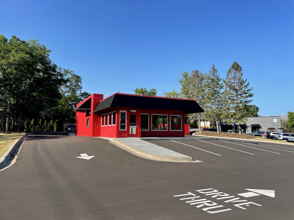This photo shows the exterior of a Red's Savoy Pizza drive-thru location, a red building that also includes dine-in and carryout.