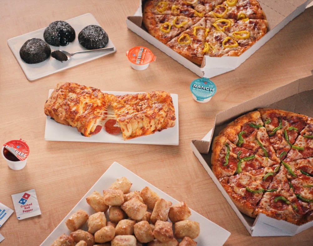 This photo shows a wide range of Domino's menu items, with the new Pepperoni Stuffed Cheesy Bread in the center along with tater tots and two different pizzas.