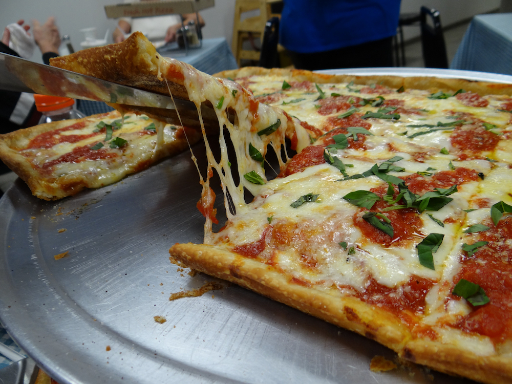 This photo shows a slice being pulled from a Margherita pizza with a nice cheese pull