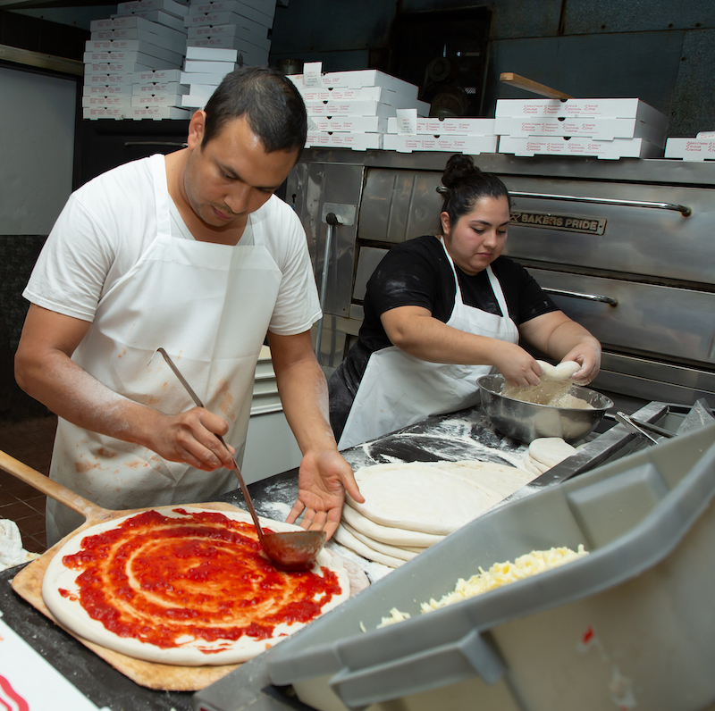 This photo shows two Armetta's team members making pizzas in the kitchen.