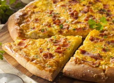 This photo shows a breakfast pizza topped with bacon, eggs and potatoes.