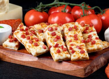 This photo shows Pizza Guys' slices of cheesy bread with about half a dozen bright-red tomatoes arrayed behind the slices.