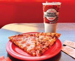 This photo shows a red plastic plate with two slices of cheese pizza and a beverage.